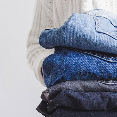 Eine Person hält einen Stapel Jeans in verschiedenen Blautönen.